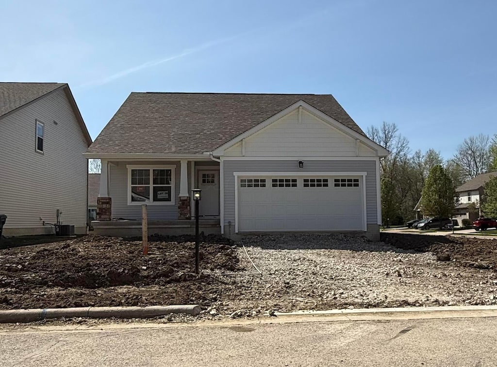 view of front facade with a garage, a porch, central AC unit, and driveway