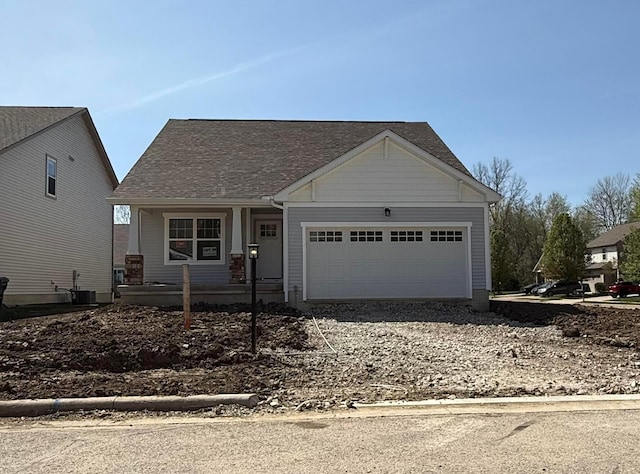 view of front facade with a garage, a porch, central AC unit, and driveway