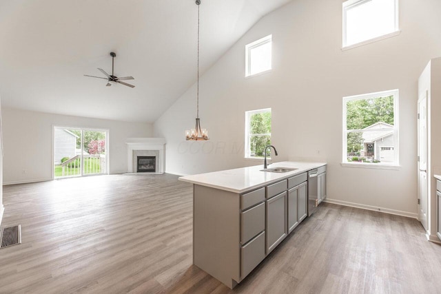 325 Woods Edge Loop, Pataskala, OH 43062 - kitchen featuring gray cabinets, a sink, high vaulted ceiling, a fireplace, and light wood-type flooring