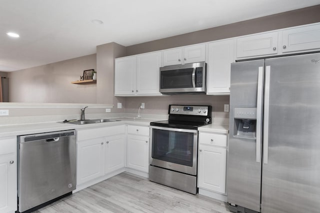 kitchen with appliances with stainless steel finishes, a sink, light countertops, white cabinetry, and recessed lighting