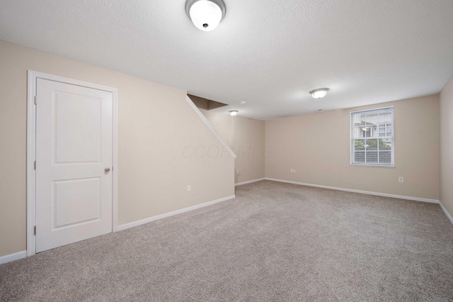 basement with carpet flooring, baseboards, and a textured ceiling