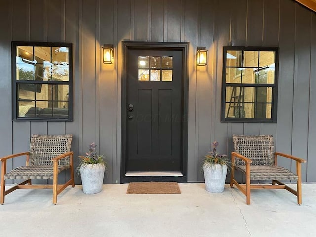 view of exterior entry with a porch and board and batten siding