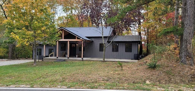 chalet / cabin featuring board and batten siding, metal roof, a porch, and a front lawn