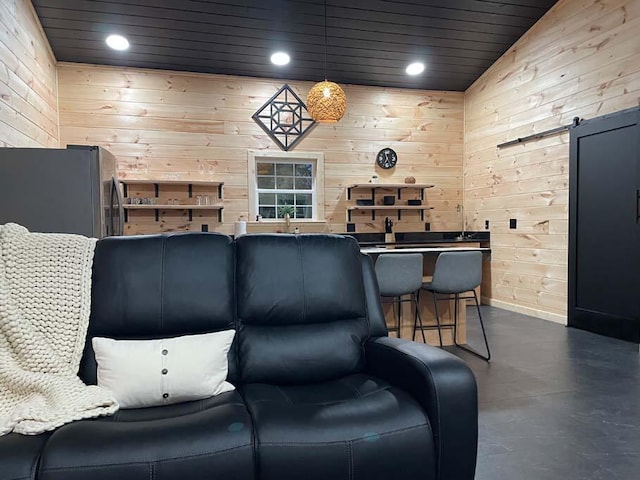 living area with recessed lighting, baseboards, wood walls, and finished concrete flooring