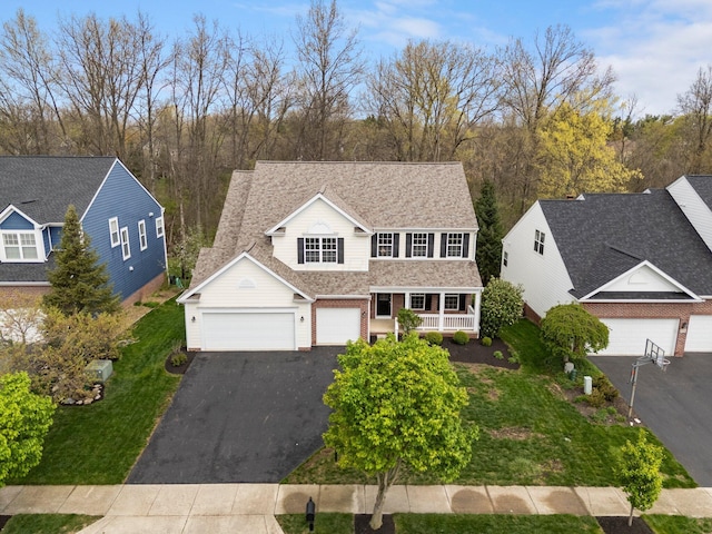 traditional-style home featuring an attached garage, driveway, a porch, and a front lawn
