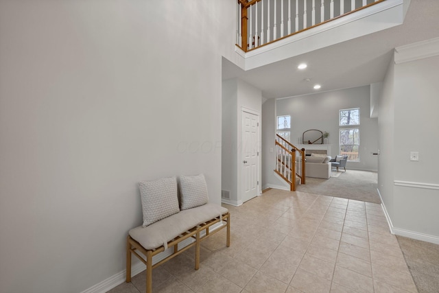 entryway featuring light tile patterned floors, light carpet, a towering ceiling, baseboards, and recessed lighting