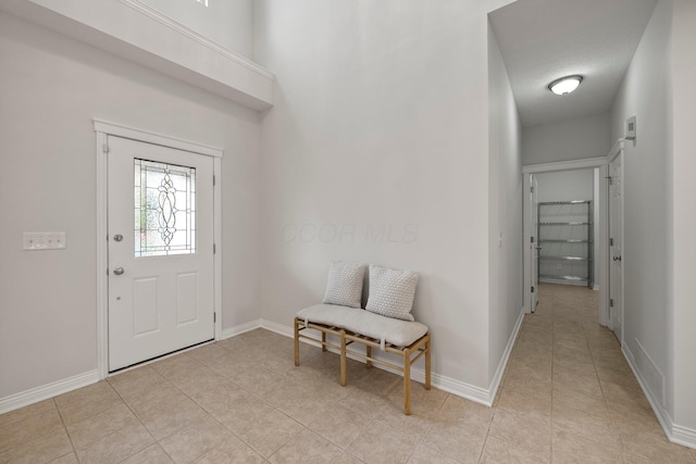 entryway with baseboards and light tile patterned floors