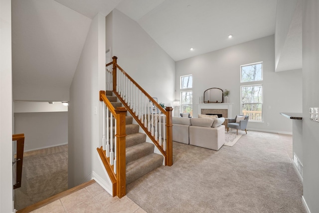 stairway with a tiled fireplace, baseboards, visible vents, and carpet
