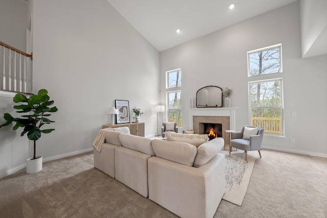 carpeted living room featuring baseboards, high vaulted ceiling, recessed lighting, and a lit fireplace