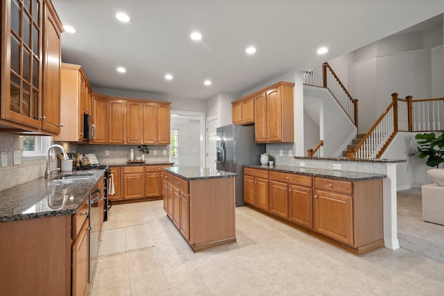 kitchen featuring glass insert cabinets, a sink, dark stone countertops, and appliances with stainless steel finishes