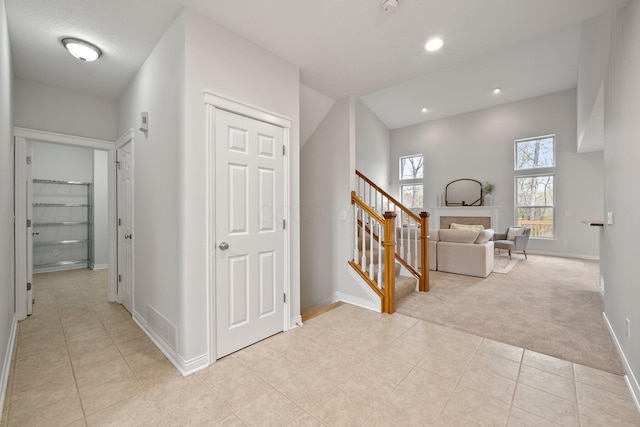 hallway featuring stairway, light tile patterned floors, light colored carpet, baseboards, and recessed lighting