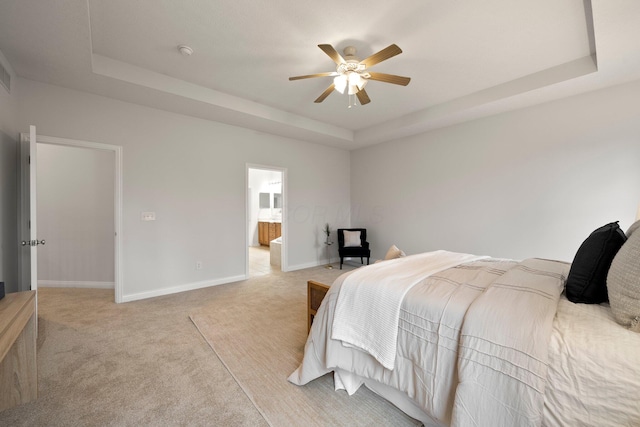 bedroom featuring connected bathroom, ceiling fan, a raised ceiling, light colored carpet, and baseboards