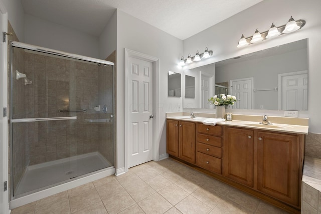 full bath with tile patterned flooring, a sink, double vanity, and a stall shower