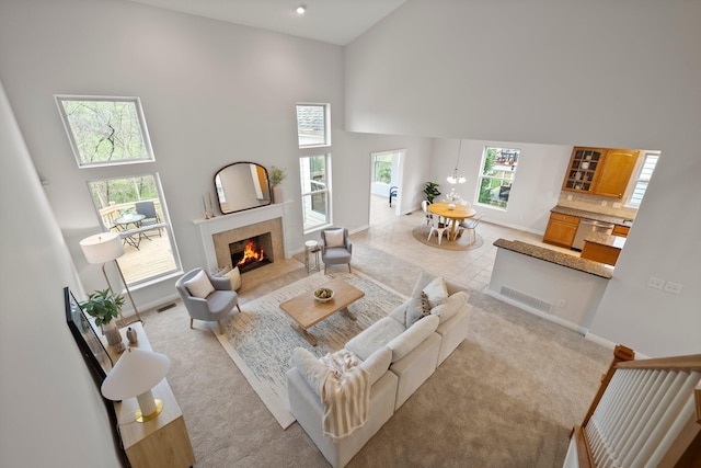 living area featuring baseboards, a tiled fireplace, high vaulted ceiling, and light colored carpet