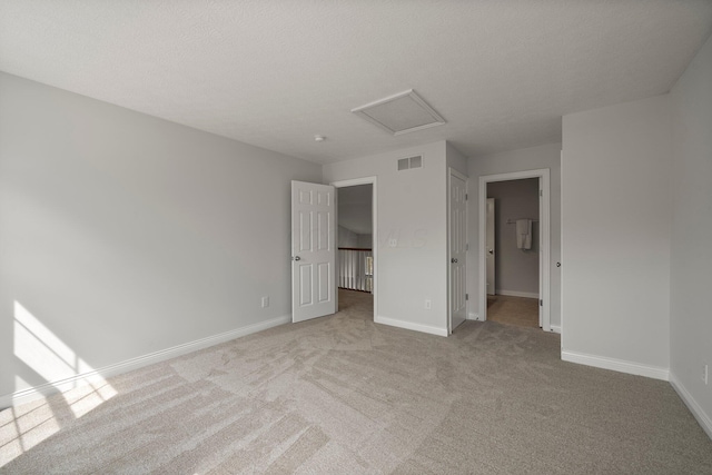 unfurnished bedroom featuring attic access, light carpet, baseboards, and a walk in closet