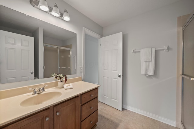 full bath with baseboards, a shower stall, tile patterned flooring, and vanity