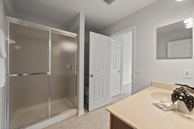 bathroom with a shower stall, vanity, toilet, tile patterned flooring, and visible vents