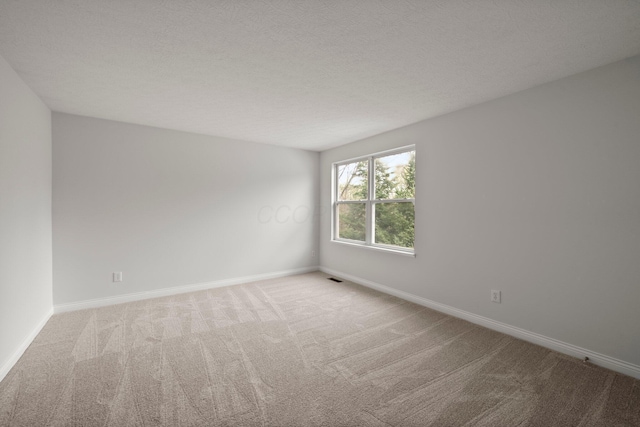 empty room featuring visible vents, baseboards, and light carpet