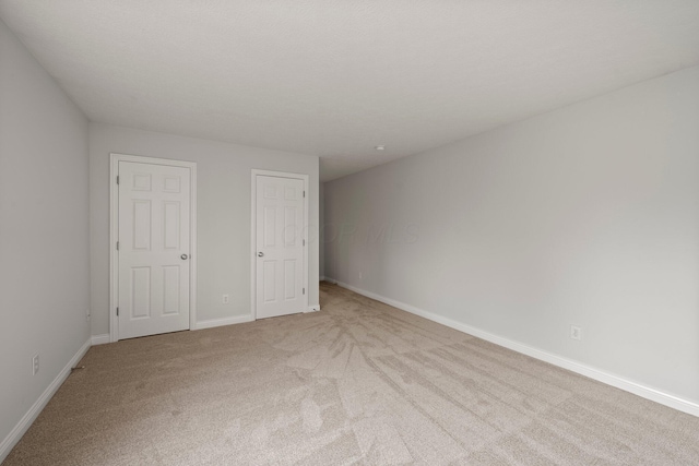 unfurnished bedroom featuring baseboards and light colored carpet