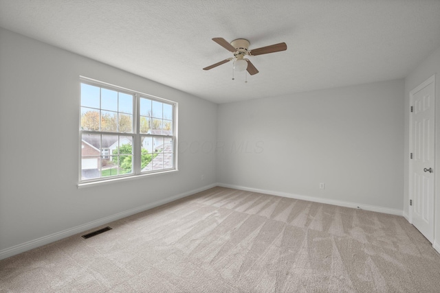 spare room featuring baseboards, visible vents, light colored carpet, and ceiling fan