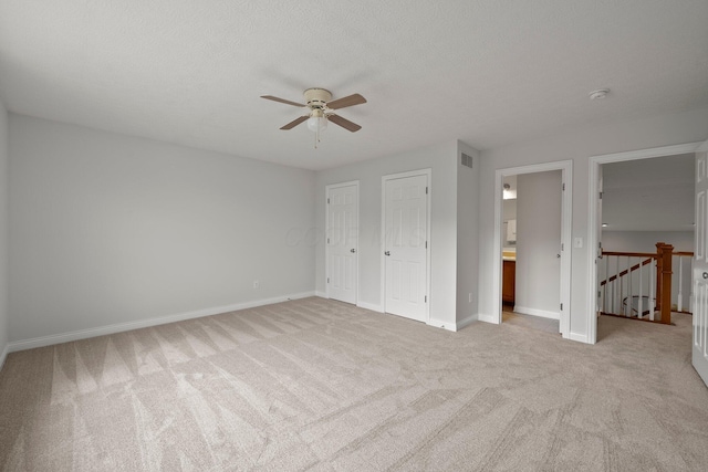 unfurnished bedroom featuring light carpet, visible vents, baseboards, ceiling fan, and connected bathroom