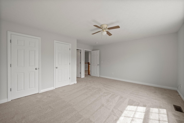 unfurnished bedroom with baseboards, a ceiling fan, visible vents, and light colored carpet
