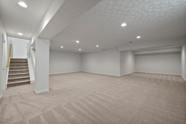 finished basement featuring light colored carpet, baseboards, a textured ceiling, and recessed lighting