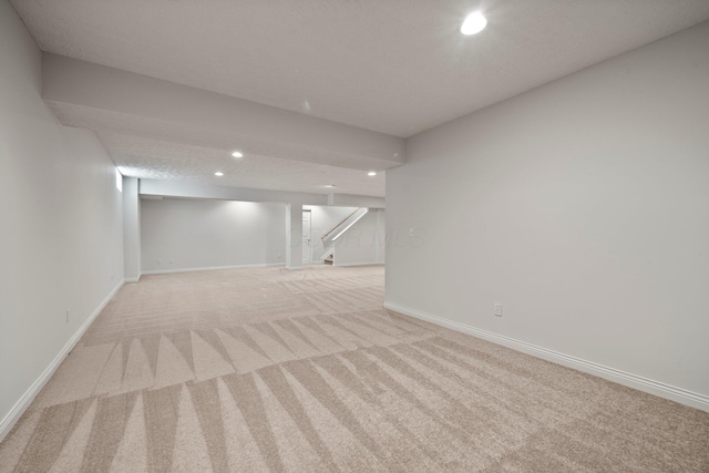finished basement featuring recessed lighting, stairs, baseboards, and light carpet