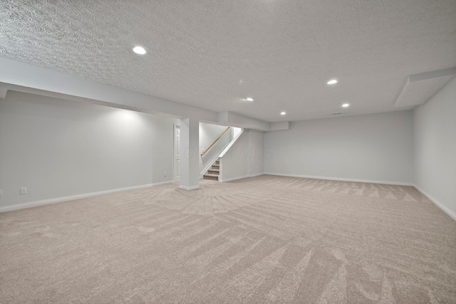 finished below grade area featuring baseboards, stairway, recessed lighting, and light colored carpet