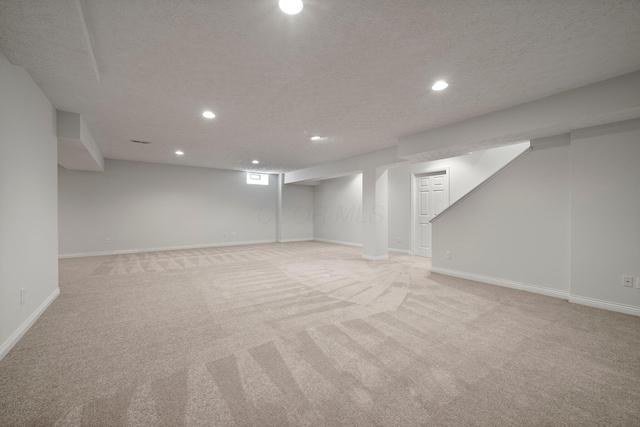 basement featuring light carpet, baseboards, and recessed lighting