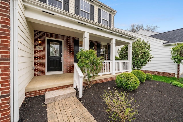 entrance to property featuring brick siding and covered porch
