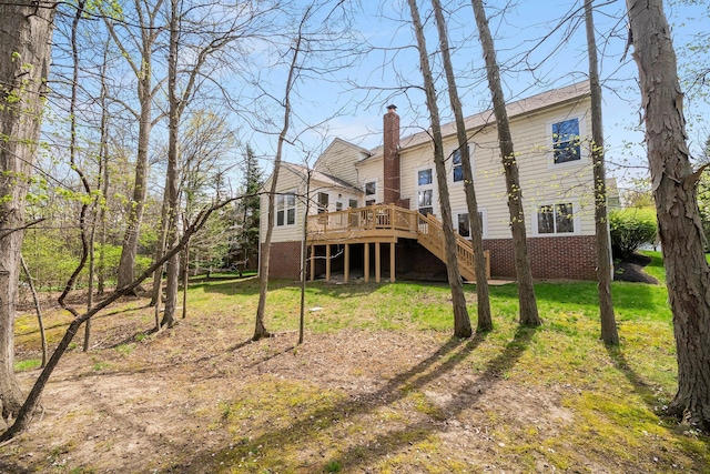 rear view of property with stairway, a chimney, a yard, brick siding, and a deck