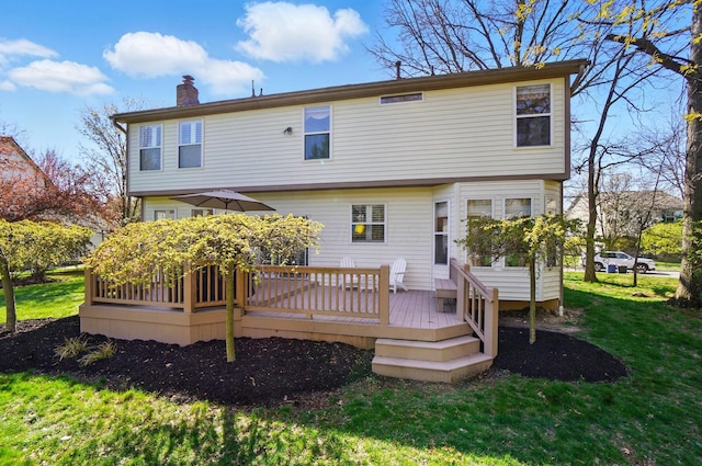 rear view of house with a chimney, a yard, and a deck