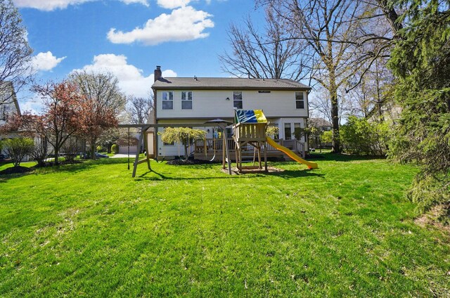 back of property with a yard, a chimney, and a playground