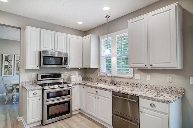 kitchen featuring light wood-type flooring, a sink, white cabinetry, and appliances with stainless steel finishes