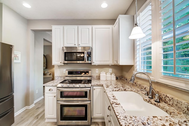 kitchen with white cabinets, baseboards, appliances with stainless steel finishes, and a sink