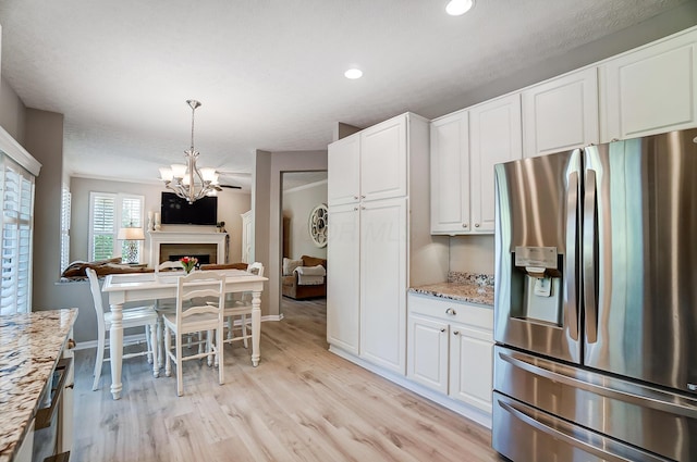 kitchen featuring open floor plan, a chandelier, light wood-type flooring, stainless steel fridge, and white cabinetry