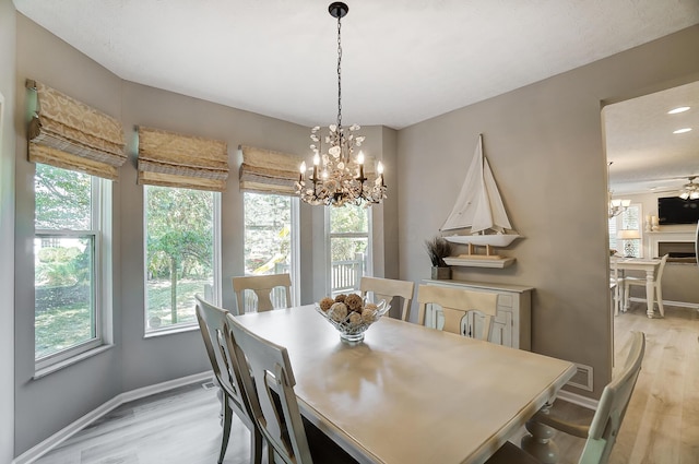 dining area featuring light wood finished floors, baseboards, and a notable chandelier