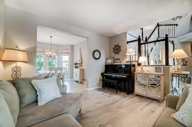 living room featuring a chandelier, wood finished floors, visible vents, and baseboards