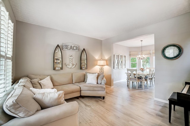 living room with light wood finished floors, baseboards, and an inviting chandelier