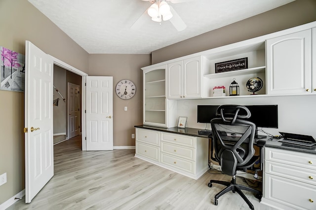 office area featuring a ceiling fan, baseboards, built in desk, and light wood-type flooring