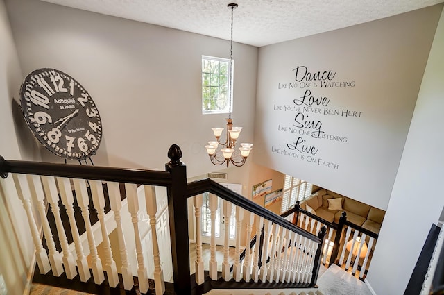 stairway with a chandelier and a textured ceiling