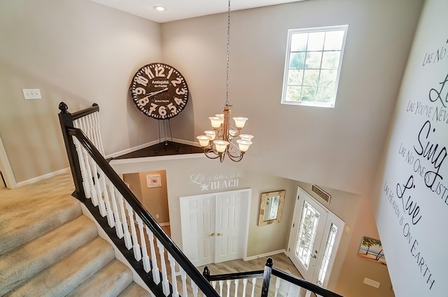 staircase with a notable chandelier, baseboards, and a healthy amount of sunlight