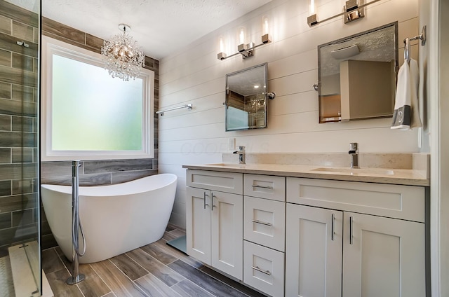 bathroom featuring a sink, an inviting chandelier, a soaking tub, double vanity, and wood finish floors