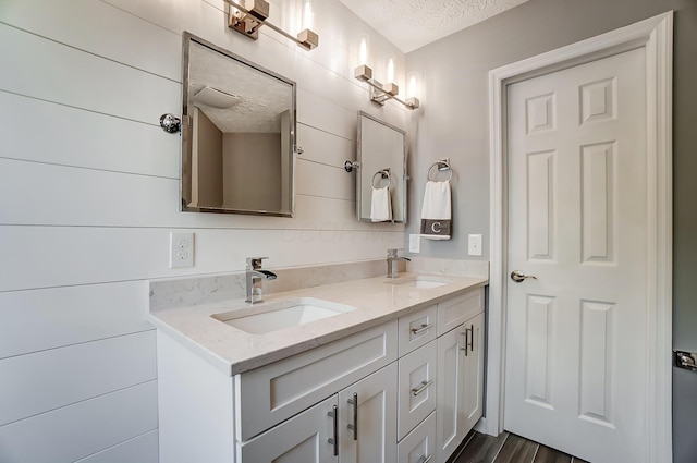 full bath featuring a sink, a textured ceiling, and double vanity