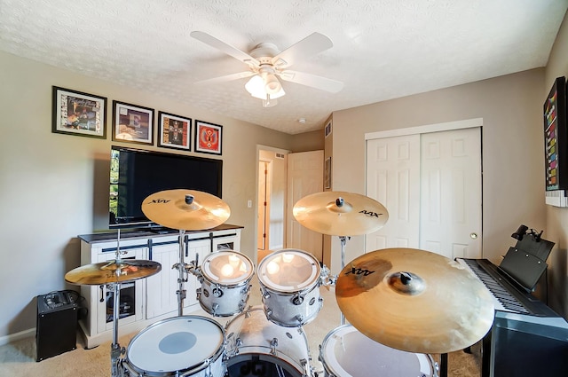 rec room featuring baseboards, a textured ceiling, a ceiling fan, and light colored carpet