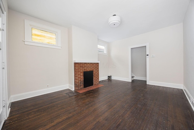 196 E Woodrow Ave, Columbus, OH 43207 - unfurnished living room with dark wood-type flooring, a brick fireplace, and baseboards