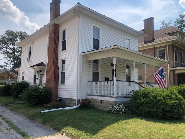 view of front of property featuring a front yard, covered porch, and a chimney