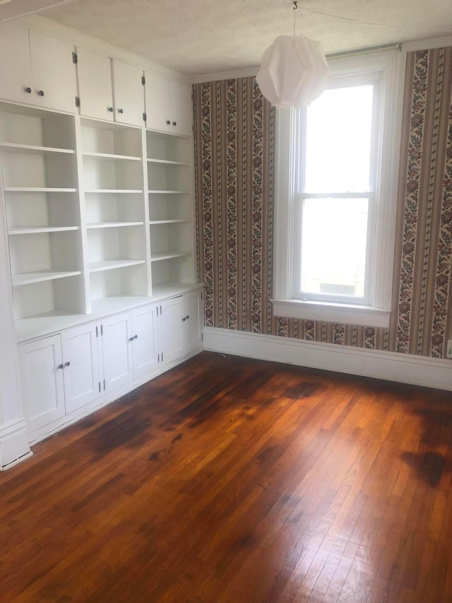 interior space featuring dark wood-style flooring, a wealth of natural light, and wallpapered walls