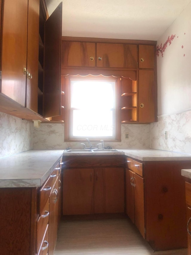 kitchen featuring open shelves, brown cabinetry, and a sink